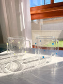 Canecas de vidro com bolinhas coloridas nas opções azul e amarela